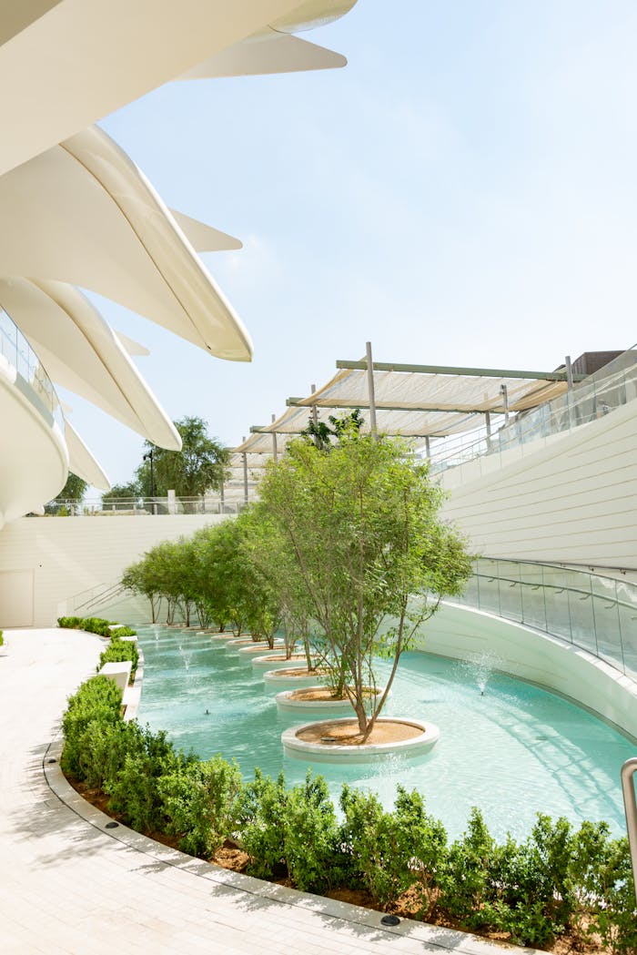 who-we-are Elegant pavilion architecture with trees and water, showcasing modern design elements.