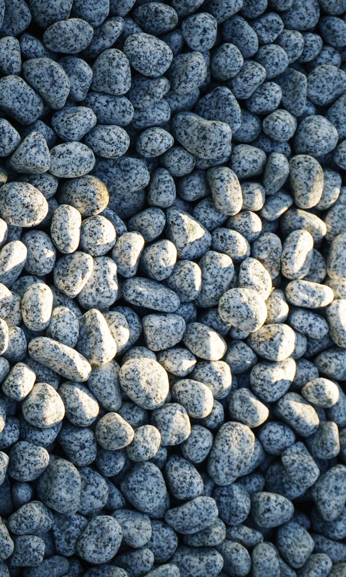 services-03 A pile of smooth granite stones illuminated by warm sunlight, creating a textured natural pattern.